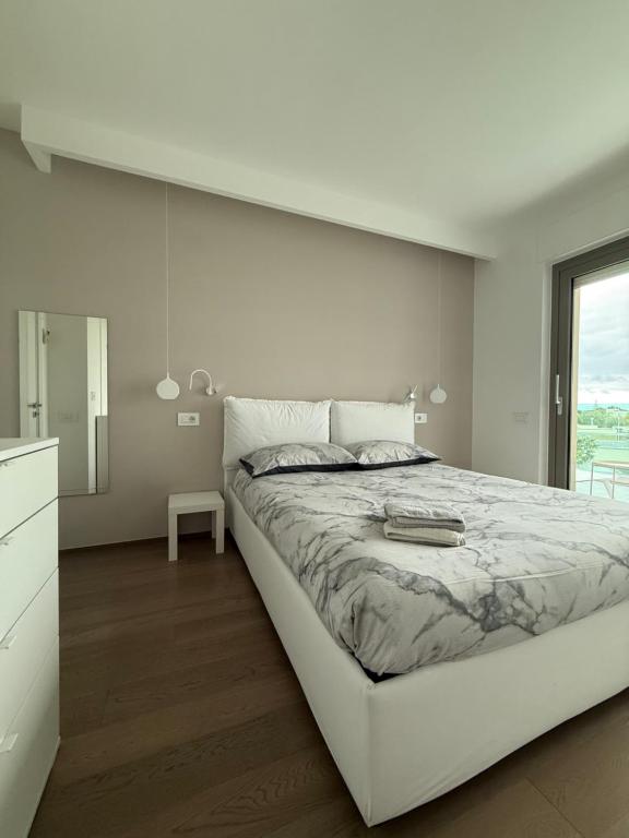 a white bedroom with a large bed and a window at Casa Clio in Noicattaro