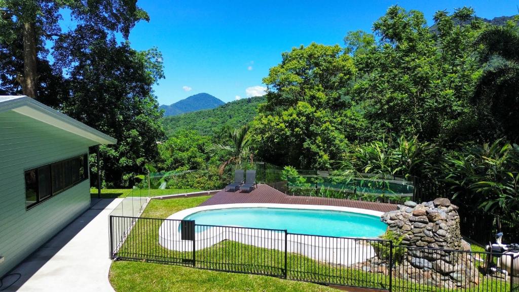 a swimming pool in a yard next to a house at Rainforest Escape with Pool & Mountain Views in Caravonica