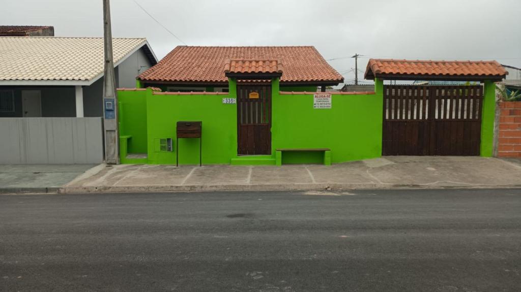 a green building with brown doors on a street at Casa Garcia in Ilha Comprida