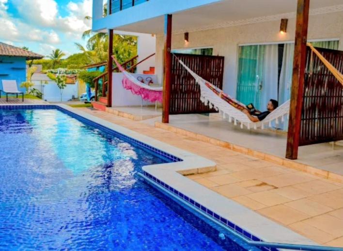 a man sitting in a hammock next to a swimming pool at Pousada Caliandra Pipa in Pipa