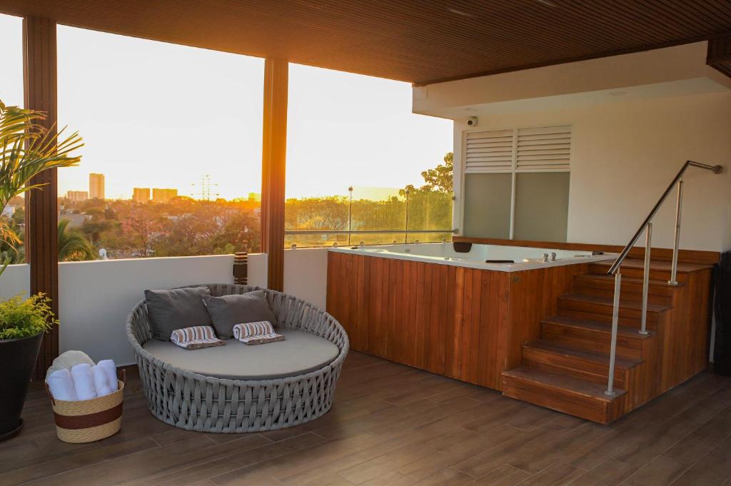 a balcony with a wicker chair and a tub and stairs at Monbelt Luxury Apartment with Rooftop Jacuzzi in Puerto Vallarta