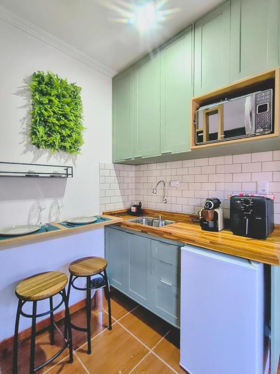 a kitchen with green cabinets and two stools at Lofts Baronesa in São José dos Campos