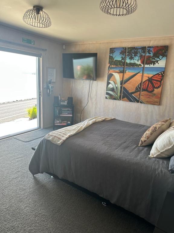 a bedroom with a bed with two paintings on the wall at Te Mata Bay Seaviews in Tapu