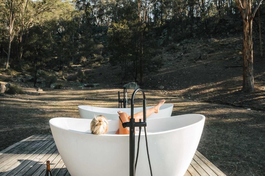 two white tubs with a woman laying in them at Tiny Maggie in Rylstone