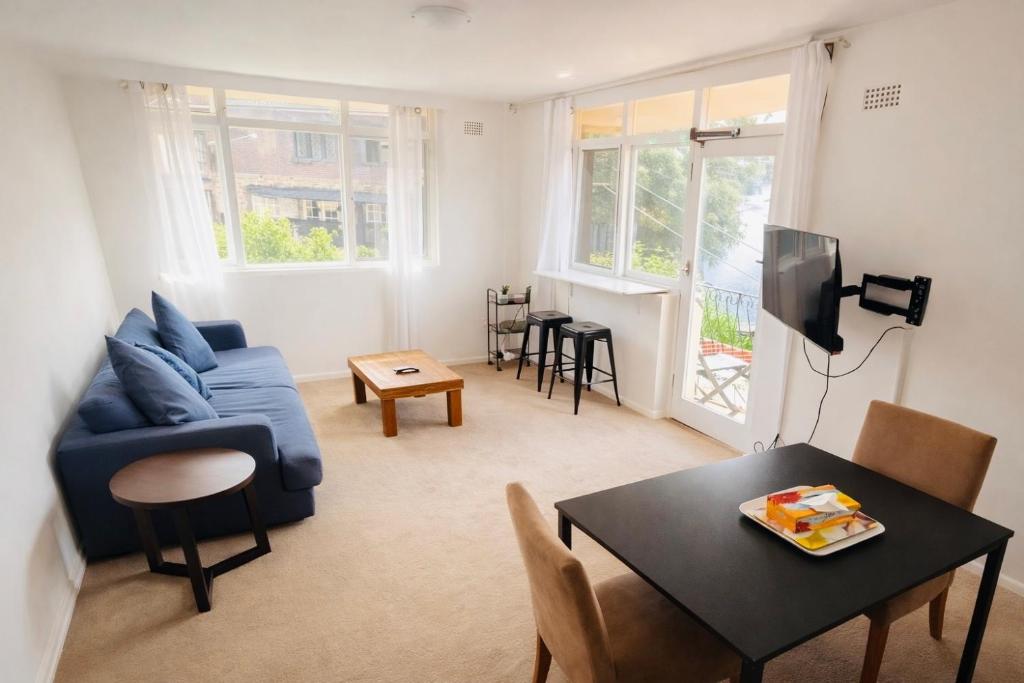 a living room with a blue couch and a table at Sydney Harbour Side Waterfront Apartment in Sydney