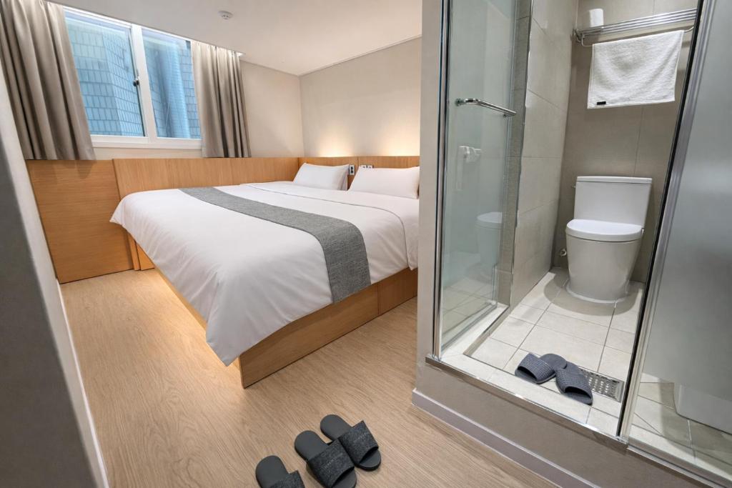 a bedroom with a bed and a shower and slippers at Sonoće Hostel Seoul - Private Bathroom & Premium in Seoul