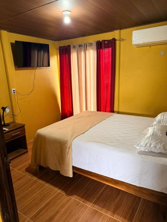 a bedroom with a bed and two red curtains at Ticary Nature Homes in Guápiles