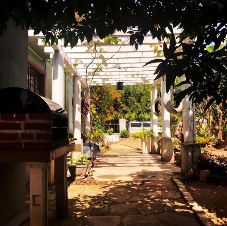 a walkway in a garden with a white pergola at Araliya in Ekala
