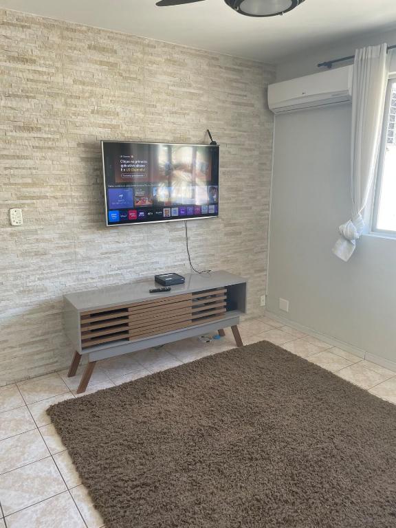 a living room with a flat screen tv on a brick wall at Campinas in São José