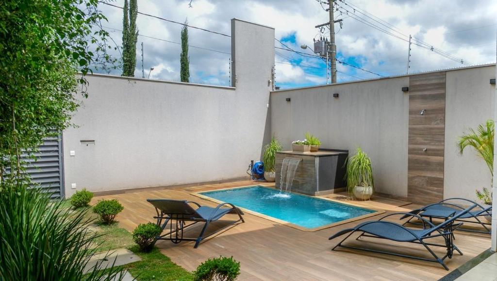 a patio with two chairs and a swimming pool at Casa com Piscina Aquecida Churrasqueira e Hidro in Franca