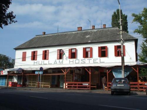 a building with a car parked in front of it at Hullam Hostel in Révfülöp