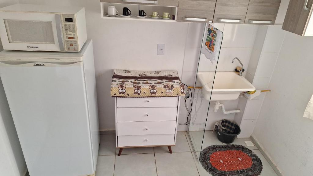 a small kitchen with a microwave and a refrigerator at Condomínio Bélgica in Presidente Prudente