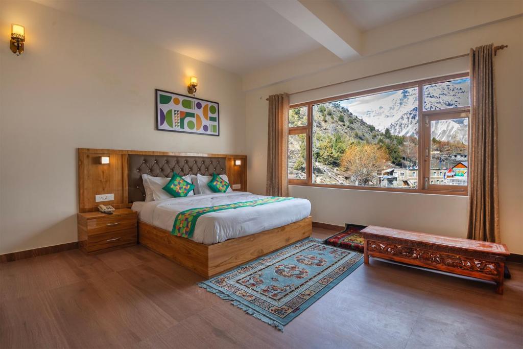a bedroom with a bed and a large window at Treebo Melag Jispa With Mountain View in Jispa