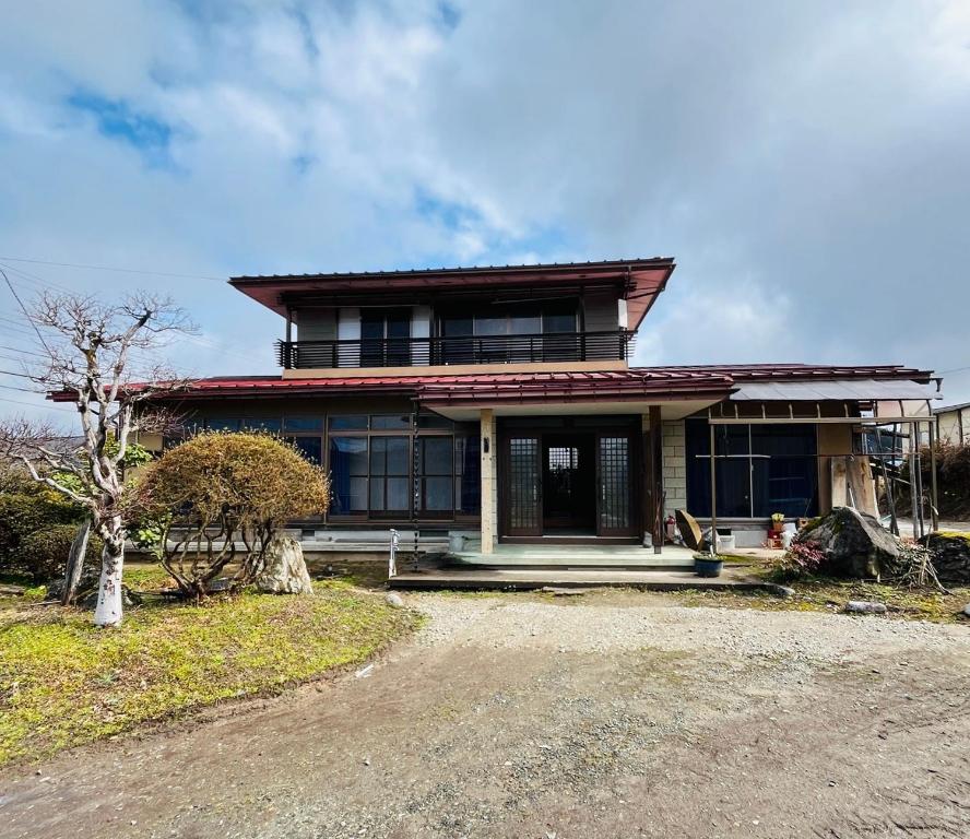 a large house with a porch on top of it at ゲストハウスさちさんち in Wagō