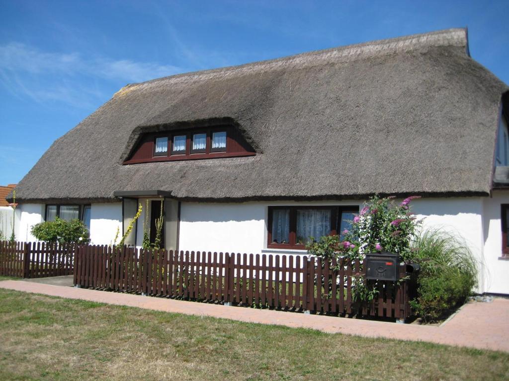 a house with a thatched roof with a fence at Apartment Neuendorf - Hiddensee 1 in Neuendorf