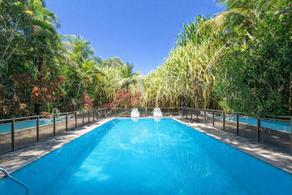 a swimming pool with two chairs in front of trees at Chacara Morada do Sol com Piscina e Churrasqueira in Sepetiba