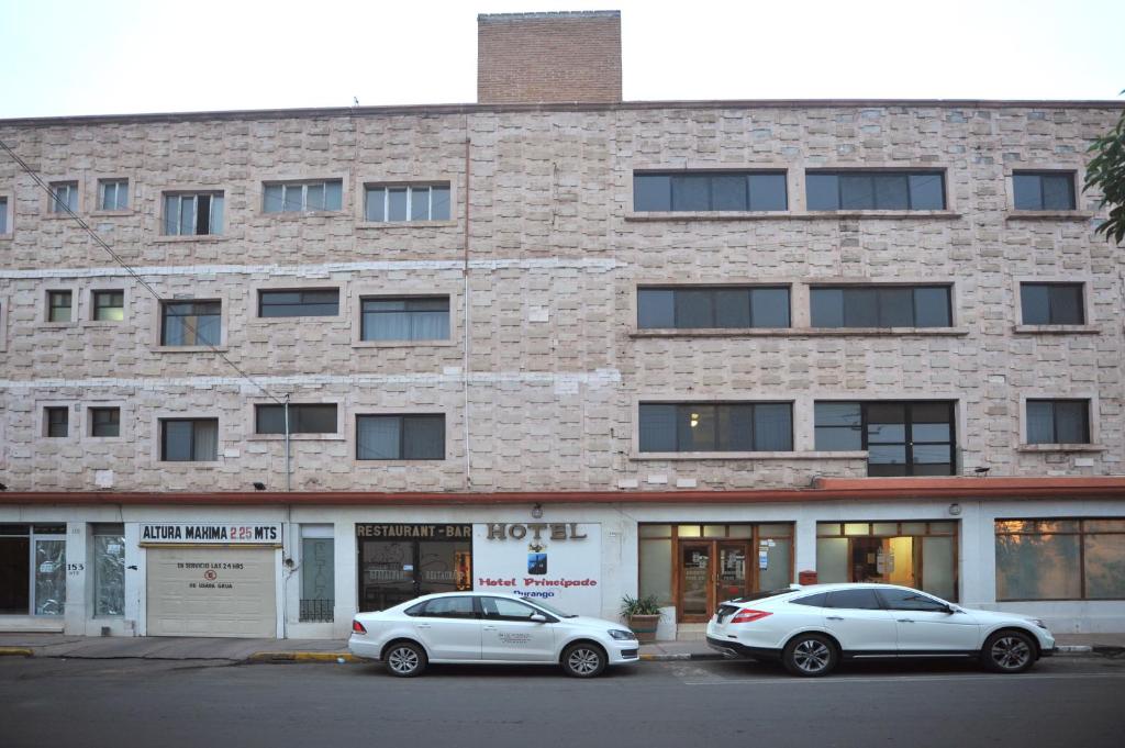 two cars parked in front of a brick building at Hotel del Principado Durango in Durango