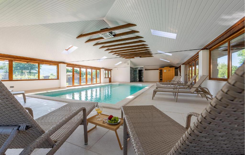 a swimming pool in a house with chairs and a table at Pet Friendly Home In Debelo Brdo With Sauna in Debelo Brdo