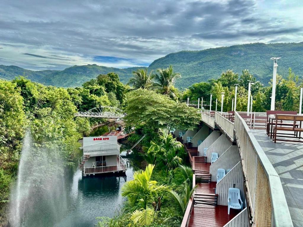 a bridge over a river with a waterfall and a boat at BAAN APA ERAWAN Resort in Ban Pong Pat