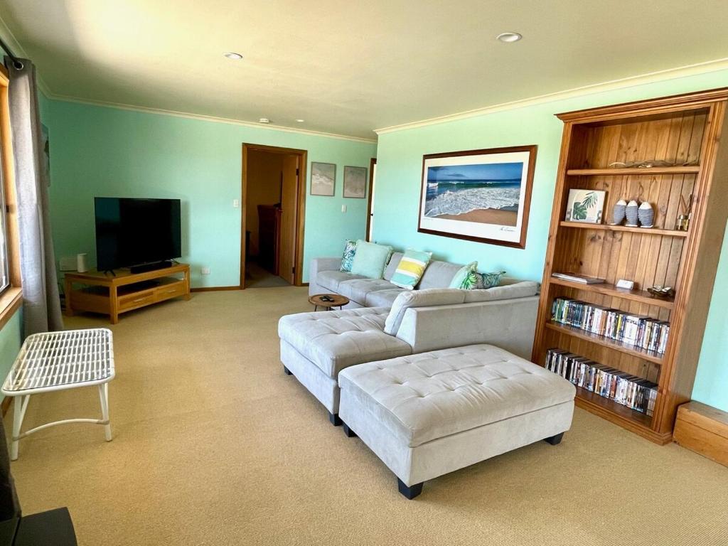 a living room with two couches and a flat screen tv at Ocean Whisper in Island Beach