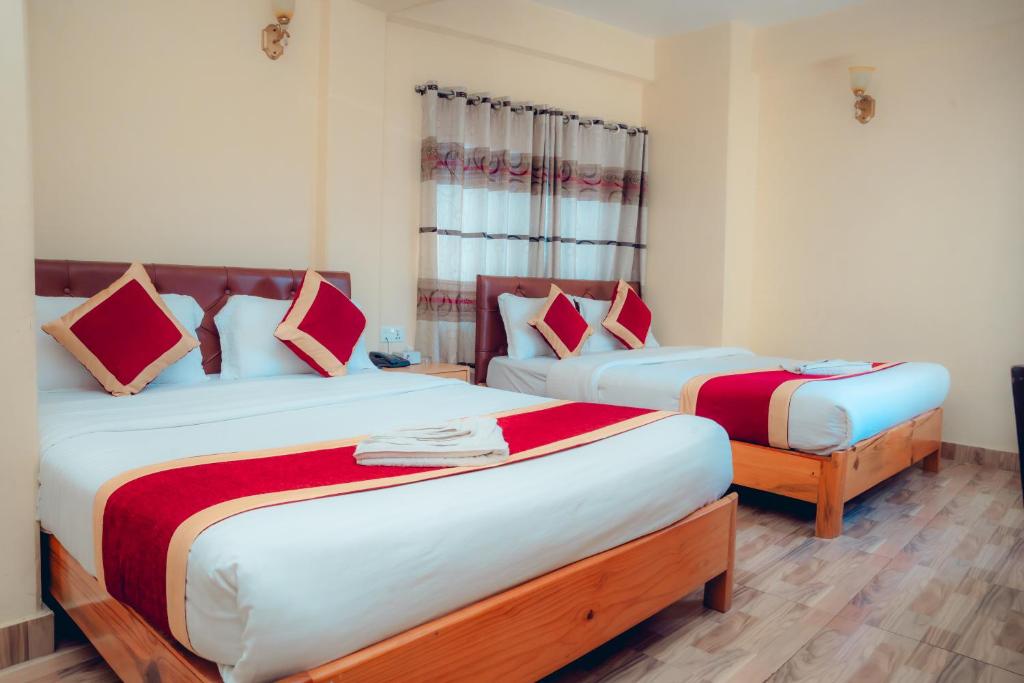 a bedroom with two beds with red and white sheets at Hotel KR Mandap in Pokhara