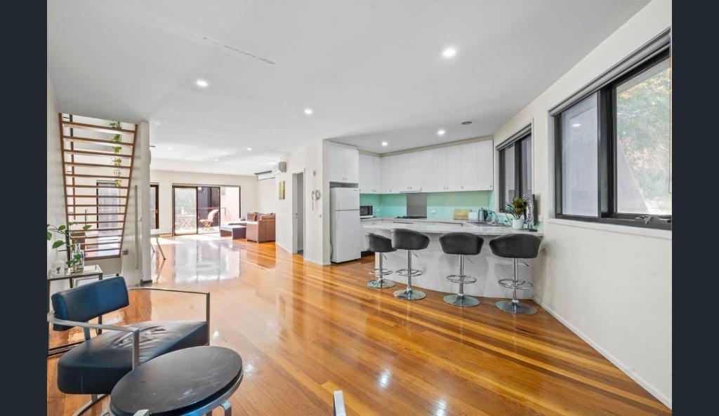 a kitchen and living room with bar stools at Convenience & Luxury Apartment in Melbourne