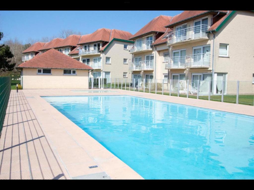 a large blue swimming pool in front of a building at Just like home De Haan aan Zee in De Haan
