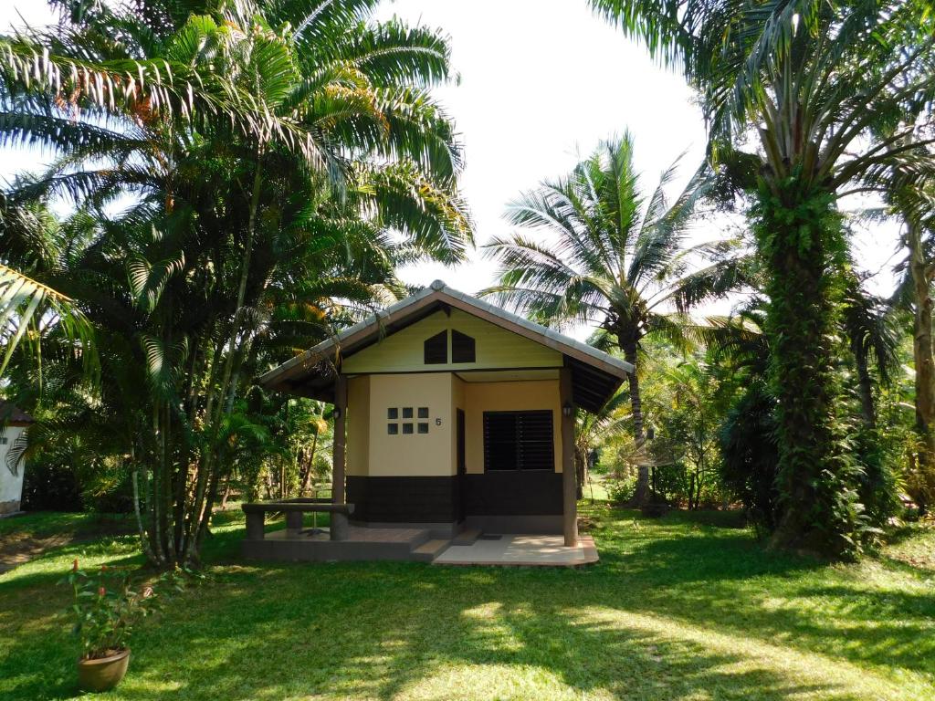 a small house in a yard with palm trees at 057 รีสอร์ท in Ban Huai To