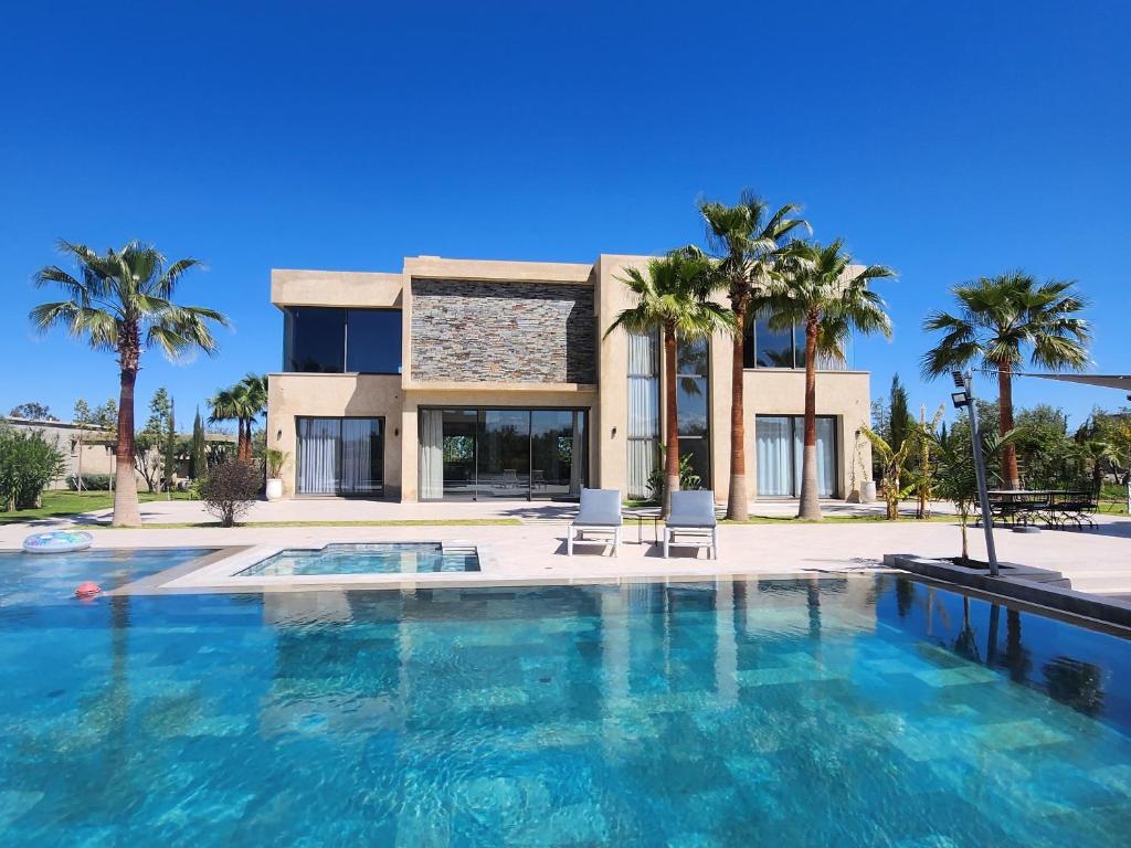 a villa with a swimming pool and palm trees at Atlas villa c3 in Sraghna