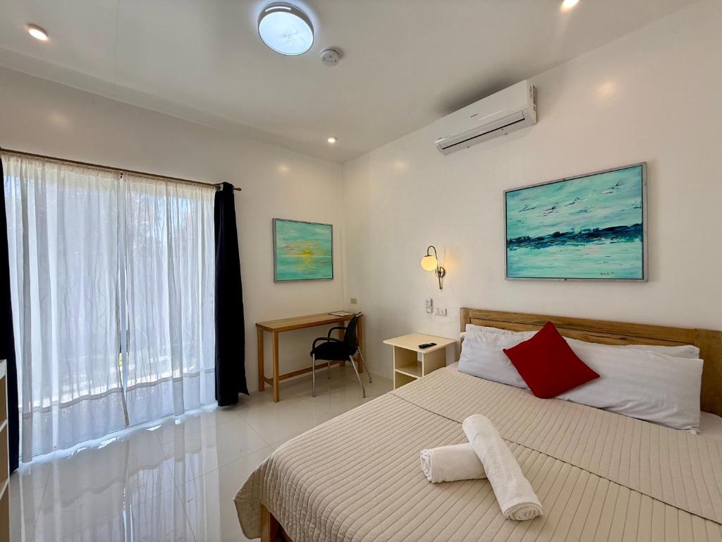 a bedroom with a bed and a desk and a window at Ivorys Guesthouse in Panglao Island