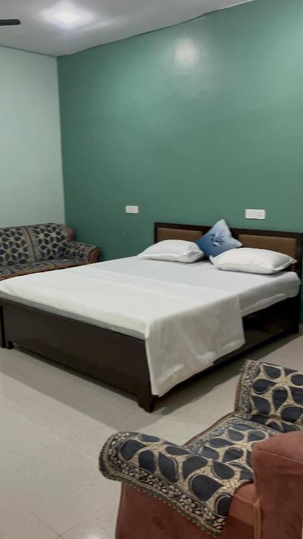 a large bed in a room with two chairs at Shyam Hotel & Janmasa in Rewa