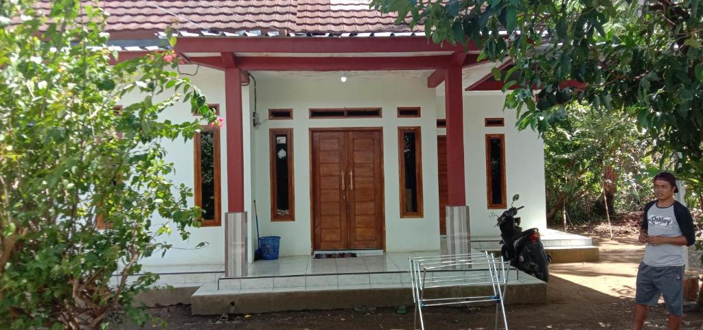a man standing in front of a small house at Veni Homestay in Batukaras