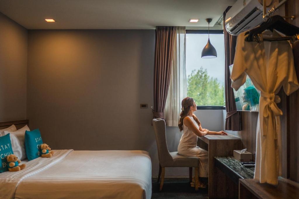 A compact in-room desk beside a window, with a double bed and open clothes rail.