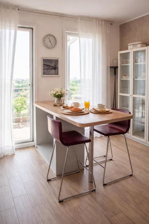 a dining room table with two chairs and a clock on the wall at SKYLINE MILANO Fiera in Milan