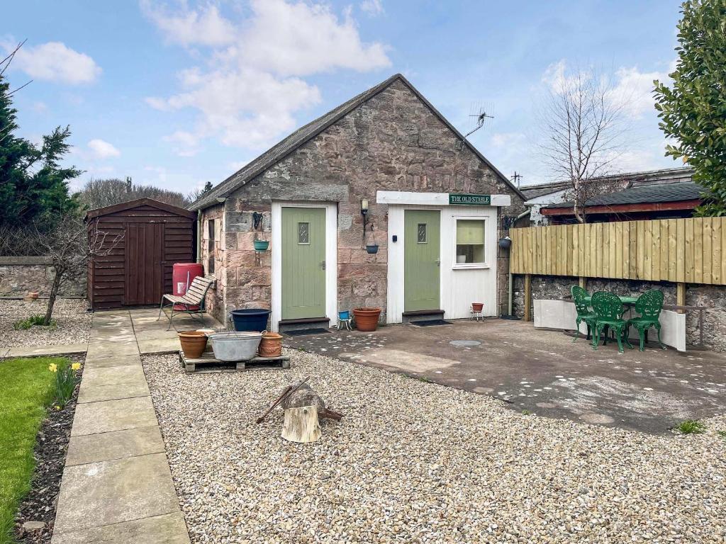 a stone house with green doors and a patio at The Stable Room - Uk51595 in Berwick-Upon-Tweed