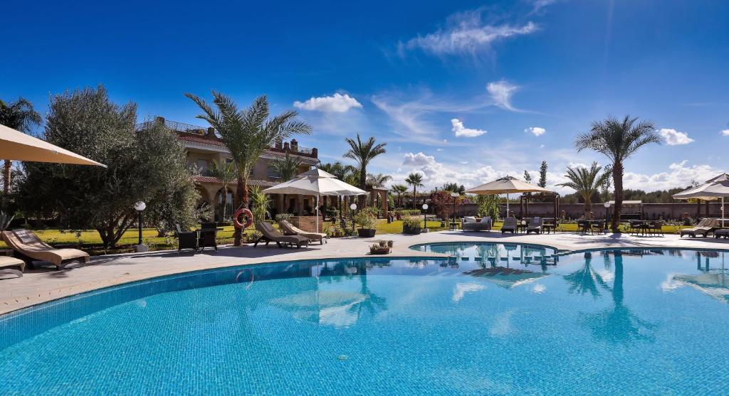 einen Pool in einem Resort mit Stühlen und Palmen in der Unterkunft Palais Amador in Oulad Mazoug