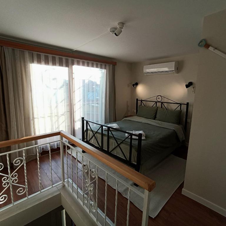 a bedroom with a bed and a balcony with a window at Dalgaci Deniz Konukevi in Ayvalık
