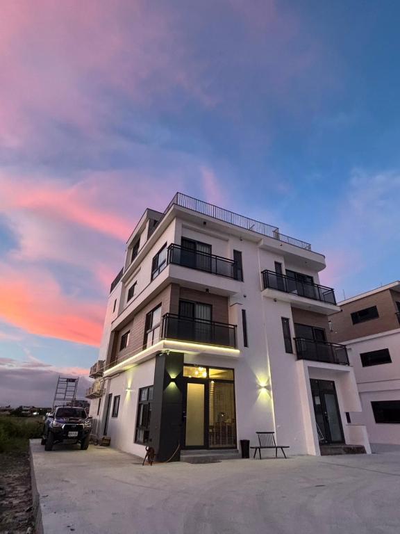 a white building with a car parked in front of it at MM No6 Villa in Luodong