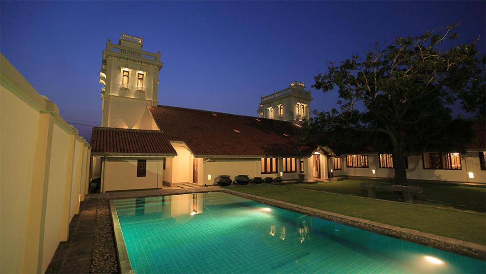 a swimming pool in front of a house at night at Monsoon Villa in Puttalam