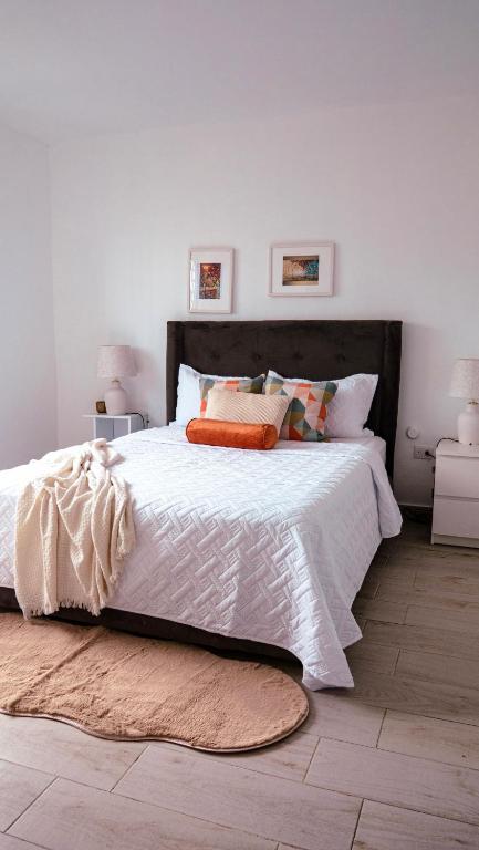 a bedroom with a bed with white sheets and orange pillows at Ankara Residence in Santo Domingo