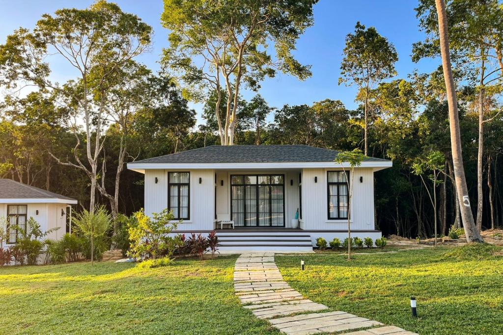 a white house with a pathway in front of a yard at Cococreek Kohkood in Ban Khlong Mat