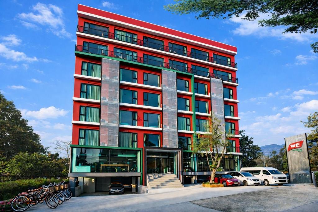 a red building with cars parked in front of it at WE Valley Hotel in Chiang Mai
