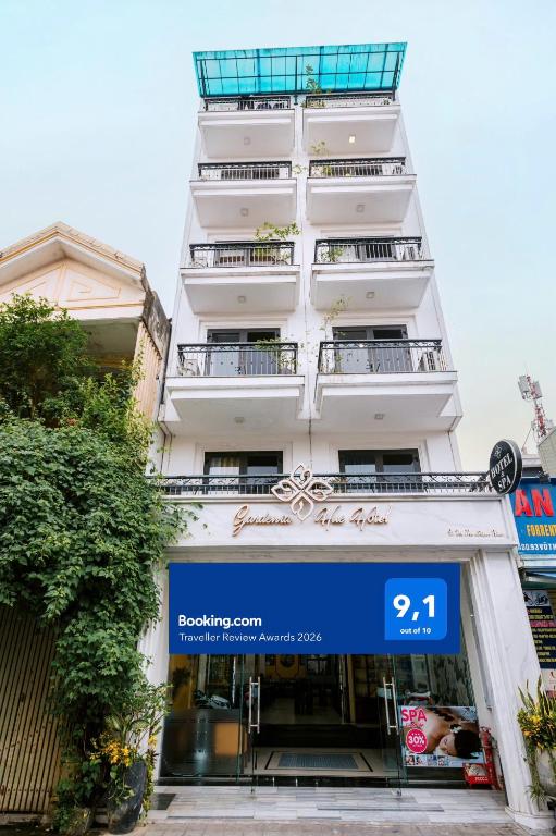 a tall white building with a sign in front of it at Gardenia Hue Hotel in Hue