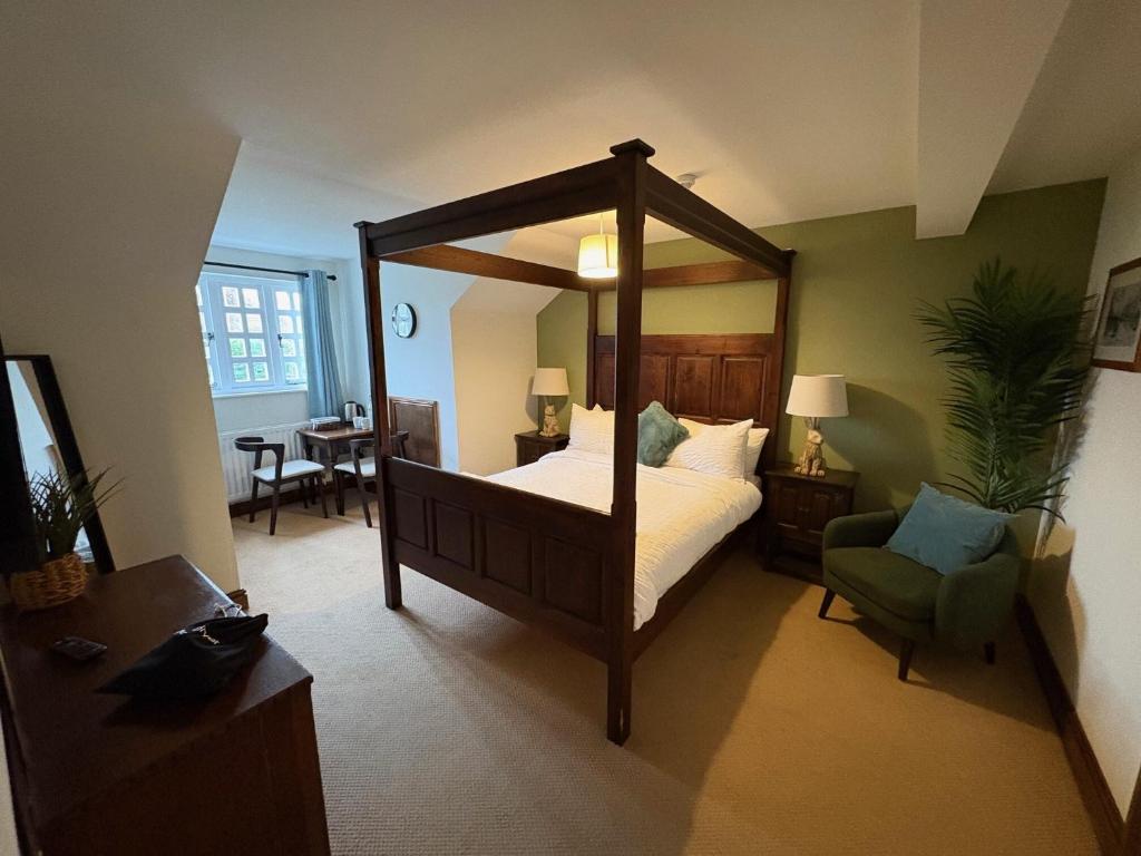 a bedroom with a large canopy bed and a chair at True Lovers Knot, Tarrant Keyneston in Tarrant Keynston