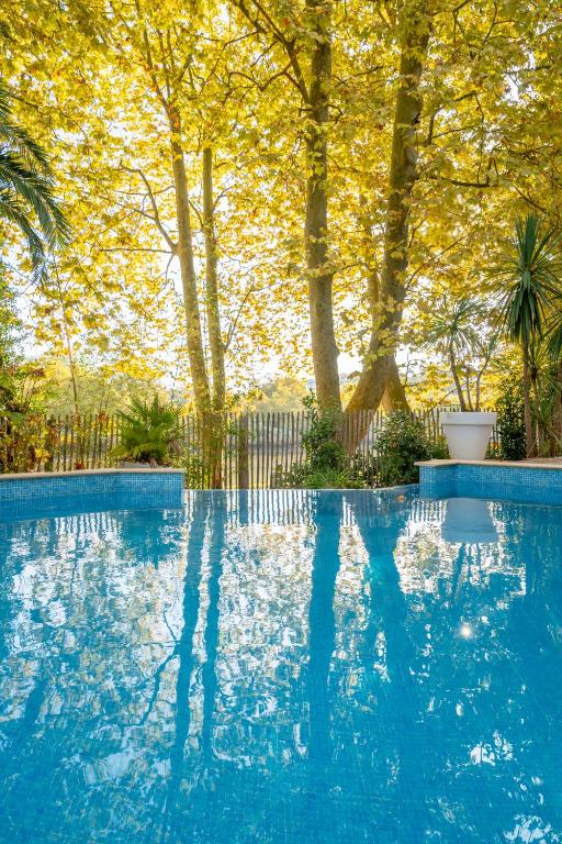 a blue swimming pool with trees in the background at Hôtel Le Bayonne in Bayonne