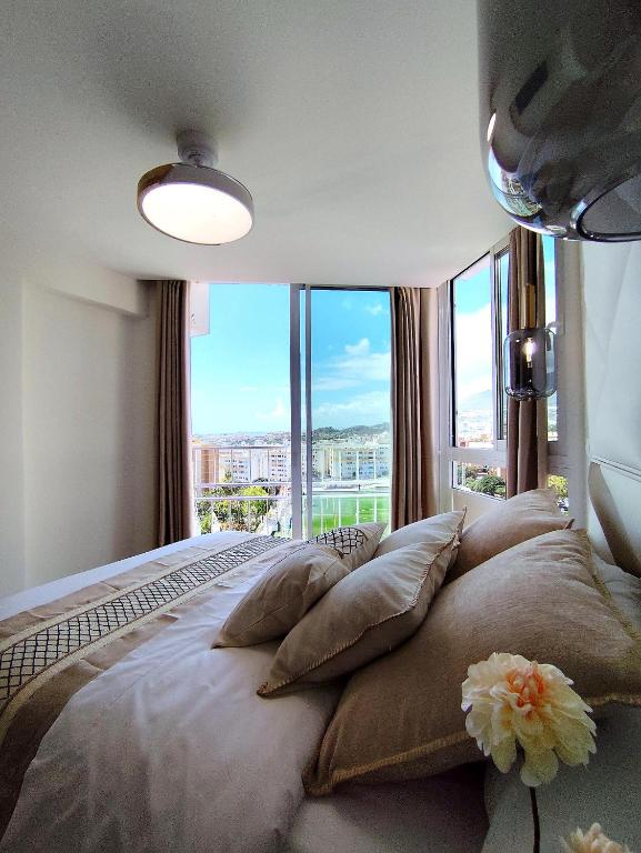 a bedroom with a large bed with pillows and a window at Blue Piscis Studio - Piscina in Benalmádena