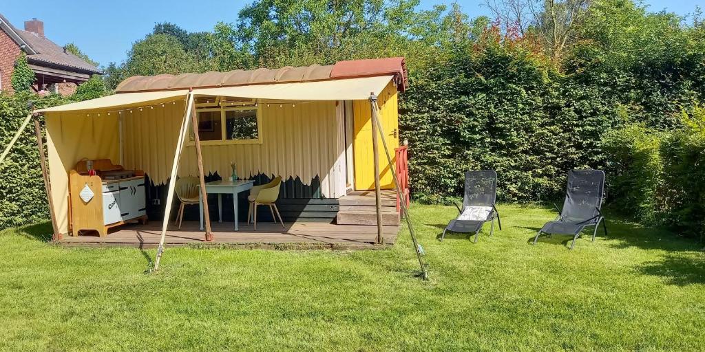a gazebo with a table and chairs in a yard at Pipowagen in Grashoek