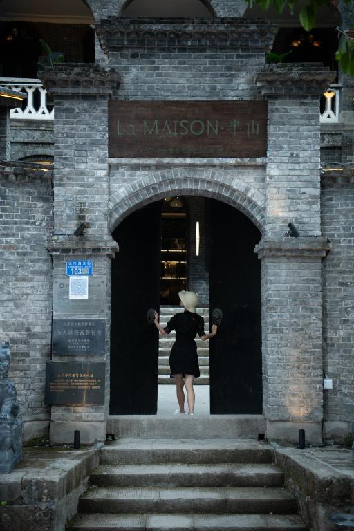 a woman in a hat exiting a building at La MAISON Banshan in Chongqing