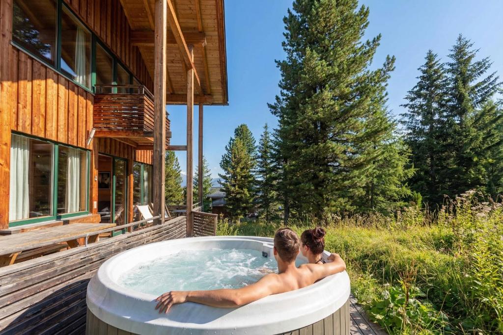 two people in a hot tub outside of a house at Alpenpark Turrach by ALPS RESORTS in Turracher Hohe