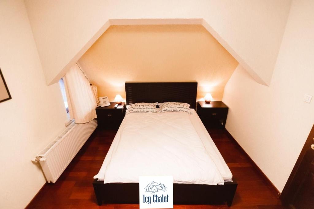 ein Schlafzimmer mit einem großen Bett im Dachgeschoss in der Unterkunft Icy Chalet in Predeal